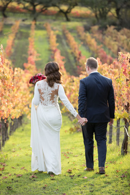Bride and groom walking hand in hand in the vineyard