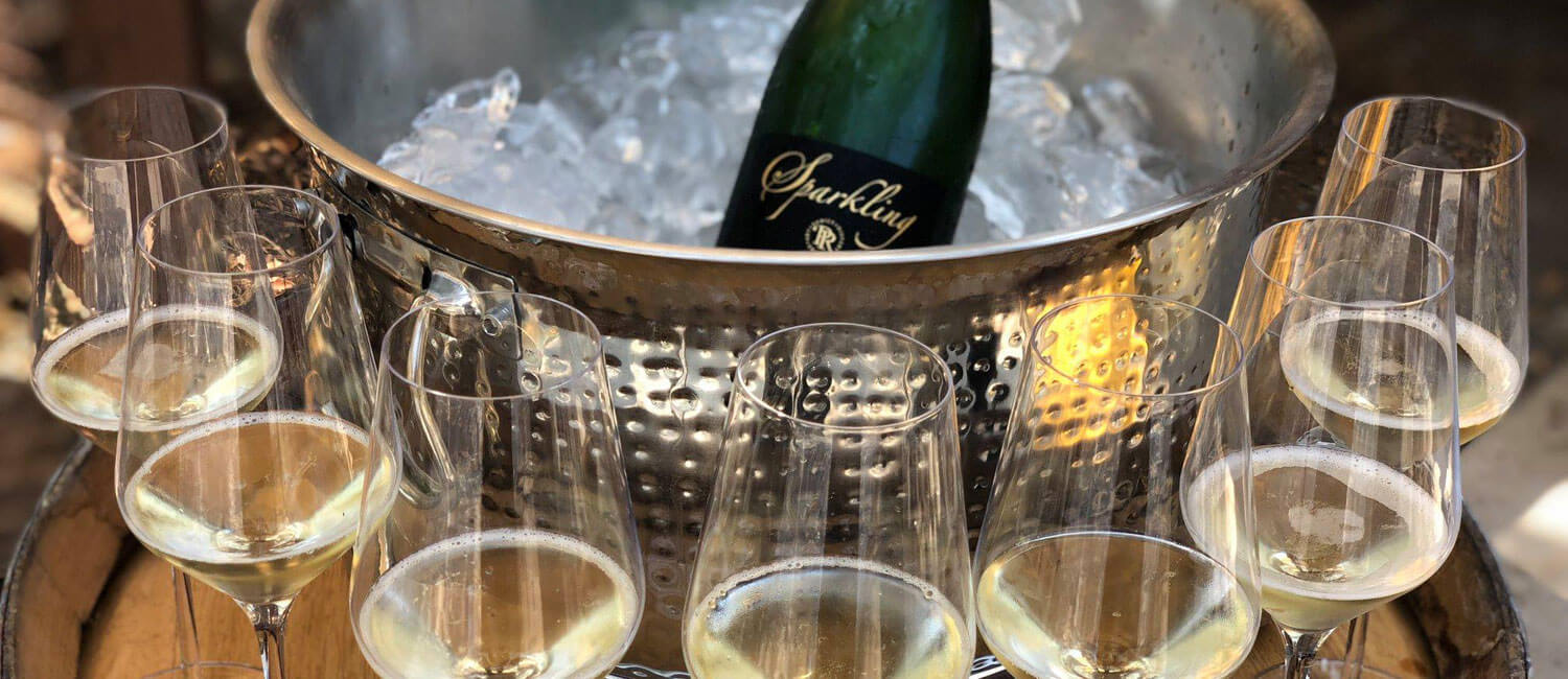 Bottle of sparkling wines on a bucket surrounded by full glasses