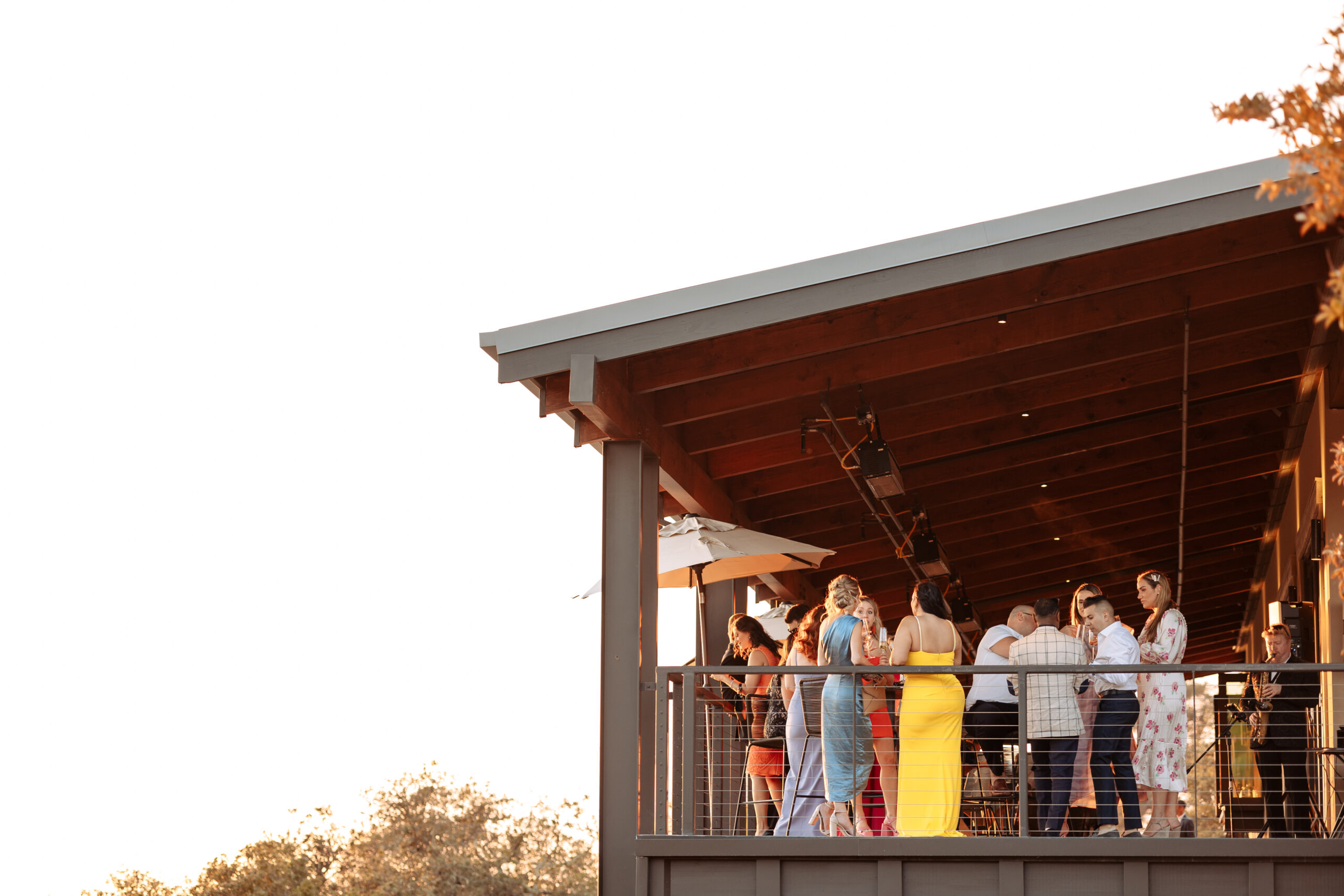 wedding guests standing on outside upper deck during sunset