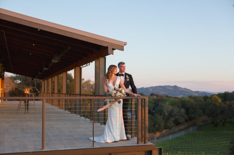 Bride and groom on the balcony overlooking the vineyard