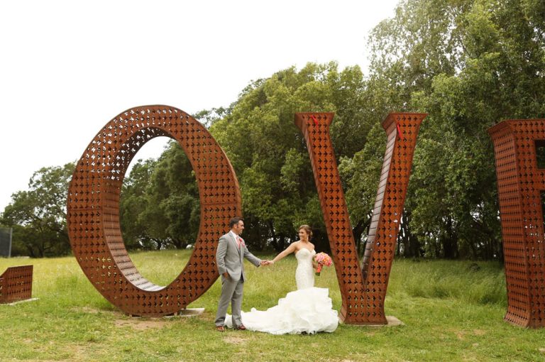 Bride and groom holding hands in front of the LOVE sculpture